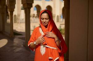 magnifique femme dans marocain traditionnel robe et tête foulard, contre beige marbre Colonnes et arches Contexte photo