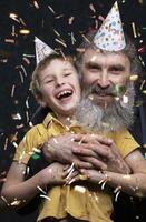 portrait de une content grand-père avec une barbe et petit fils de le anniversaire garçon sur une noir Contexte. photo