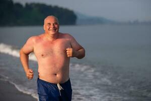 un personnes âgées homme de athlétique construire est le jogging le long de le bord de mer.le homme va dans pour des sports. photo