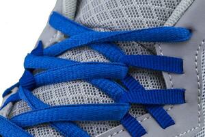 une fragment de une gris baskets avec bleu lacets proche en haut. baskets texture photo