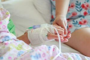 mère en portant enfant main avec saline iv Solution dans hôpital photo