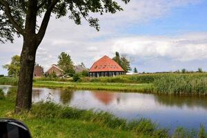 une maison avec une rouge toit et une étang dans le Contexte photo