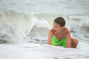 content garçon baignades dans le mer, pièces avec vagues et éclaboussures. photo