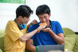 portrait de deux Jeune asiatique gay des couples séance sur canapé, dépenses leur gratuit temps et en train de regarder la télé à Accueil ensemble, concept pour mode de vie de lgbt gens autour le monde. photo