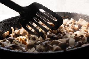 cuisson des champignons frits avec des oignons, remuez les champignons photo