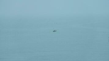 le paisible mer vue avec le pêche bateau voile sur il dans le nuageux journée photo