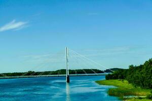 une pont couvrant plus de une rivière avec des arbres et herbe photo