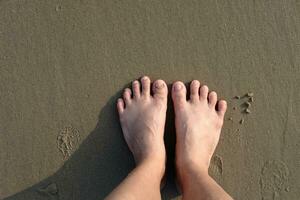 asiatique femme pieds sur le sablonneux plage avec Naturel lumière du soleil. été mer Haut vue photo
