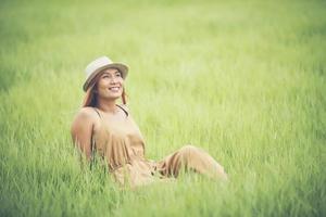 jeune femme assise se sentir bien dans le champ d'herbe. photo