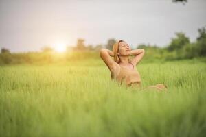 jeune femme assise se sentir bien dans le champ d'herbe. photo