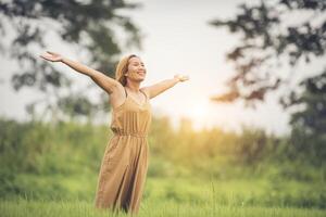 jeune femme debout dans le champ d'herbe levant les mains en l'air. photo