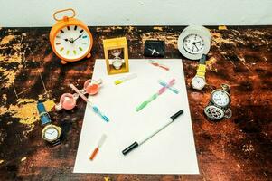 une table avec divers articles comprenant horloges, des stylos, et une stylo photo