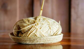 une fil avec une tricot aiguille coincé dans il mensonges sur une en bois table, passe-temps artisanat avec fil, main fait. photo