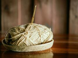 une fil avec une tricot aiguille coincé dans il mensonges sur une en bois table, passe-temps artisanat avec fil, main fait. photo