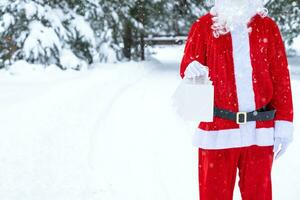 le père noël en plein air en hiver et dans la neige remet des sacs en papier à main avec cadeau artisanal, livraison de nourriture. shopping, recyclage des emballages, fait main, livraison pour noël et nouvel an photo