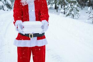 conteneurs de service de livraison de nourriture dans les mains du père noël en plein air dans la neige. promotion de la veille de noël. commande chaude prête à l'emploi, boîte en plastique jetable. restauration des vacances du nouvel an. espace de copie, maquette photo