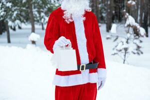 le père noël en plein air en hiver et dans la neige remet des sacs en papier à main avec cadeau artisanal, livraison de nourriture. shopping, recyclage des emballages, fait main, livraison pour noël et nouvel an photo