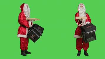 père Noël costume livreur porter thématique sac à dos avec vite nourriture commande, Noël vacances livraison concept. Saint pseudo posant contre plein corps écran vert Contexte. photo