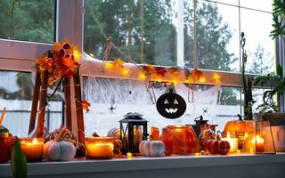 de fête décor de le maison sur le rebord de fenêtre pour Halloween - citrouilles, jack o lanternes, crânes, toiles d'araignées, araignées, squelettes, bougies et une guirlande - une confortable et terrible ambiance photo