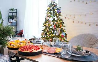 portion une de fête table avec collations, salades et goodies fermer dans le moderne intérieur de une grenier maison décoré pour Noël et Nouveau an. attendre pour invités pour une de fête dîner photo