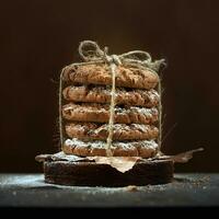 les biscuits au chocolat dans une pile attachée avec une corde sont saupoudrés de sucre en poudre sur un fond marron. photo