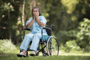 Femme âgée seule assise triste sentiment sur fauteuil roulant au jardin photo