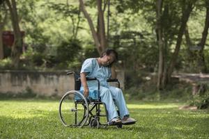 Femme âgée seule assise triste sentiment sur fauteuil roulant au jardin photo