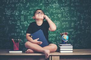 petit garçon réfléchi avec un livre près d'une commission scolaire photo