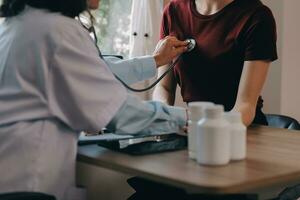 asiatique médecin femme a visité patient femme à diagnostic et vérifier en haut santé à Accueil ou privé hôpital. femelle patient Explique santé problème et symptômes à médecin .santé se soucier prime un service à Accueil photo