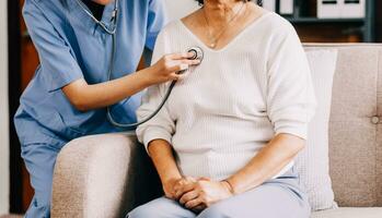 Dame à venir à clinique pour cœur et poumons vérification, Masculin médecin en utilisant stéthoscope, écoute à femelle les patients souffle ou battement de coeur, séance dans clinique Bureau photo