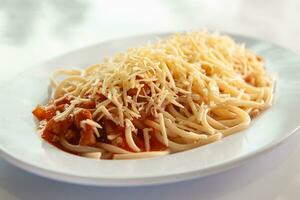 spaghetti bolognaise avec fromage saupoudré est mis sur une blanc assiette avec une blanc Contexte photo