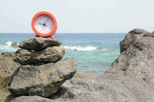 une rouge l'horloge séance sur Haut de une pile de rochers photo