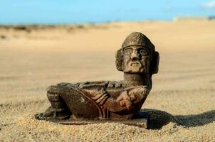 ancien statue de une homme séance sur le le sable photo