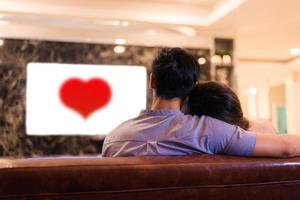 jeunes amants asiatiques regardant la télévision sur un canapé