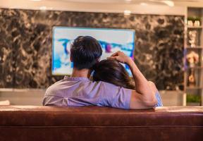 jeunes amants asiatiques regardant la télévision sur un canapé