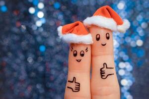 doigt art de couple fête Noël. concept de homme et femme en riant dans Nouveau année Chapeaux. content paire montrant les pouces en haut. tonique image. photo