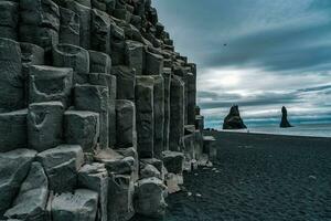 reynisdrangar Naturel Roche formation sur reynisfjara noir le sable plage dans sombre journée à Islande photo