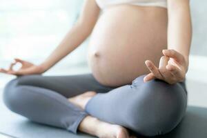 Enceinte femme Faire yoga sur exercice tapis. méditer pour à court terme accouchement de méditer attrayant Enceinte femelle des loisirs et se détendre, respiration et calme avec yoga. soi se soucier photo