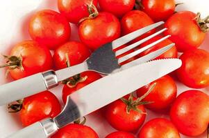 une couteau et fourchette sont séance sur Haut de une bol de tomates photo