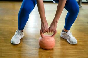 fermer et surgir Jeune femelle faire des exercices avec kettlebell poids dans aptitude centre. photo