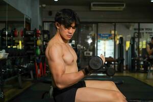 fermer asiatique gars avec parfait corps en jouant poids formation à aptitude centre. photo