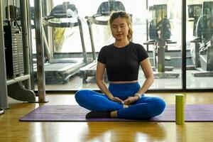 asiatique Jeune femelle formation yoga dans aptitude centre sur brillant Contexte. photo