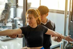 fermer et surgir asiatique Jeune femelle formation yoga avec sa entraîneur dans aptitude centre sur brillant Soleil éclater Contexte. photo