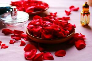 Rose pétales dans bol et parfum bouteille sur rose nappe de table. photo