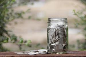 tirelire en verre bouteille avec des pièces de monnaie en baht thaïlandais. économiser de l'argent concept photo