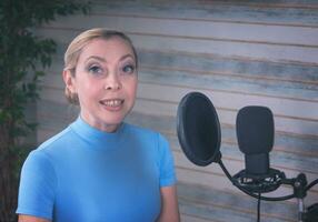 une fille dans une bleu col roulé est en train de préparer pour une Podcast avec une microphone. grand ficus dans le Contexte photo