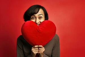 portrait de une content femme avec rouge cœur sur une rouge background.valentine's journée concept ai généré photo