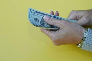 mains dans une gris chandail avec dollar factures sur une Jaune Contexte. femelle mains en portant dollar argent, fermer. photo