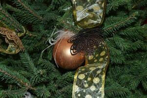 Nouveau années décoration dans le forme de une d'or Balle avec une ruban sur le Noël arbre. de fête Contexte. photo
