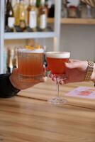 deux alcoolique des cocktails dans mains plus de une en bois cafétéria tableau. photo